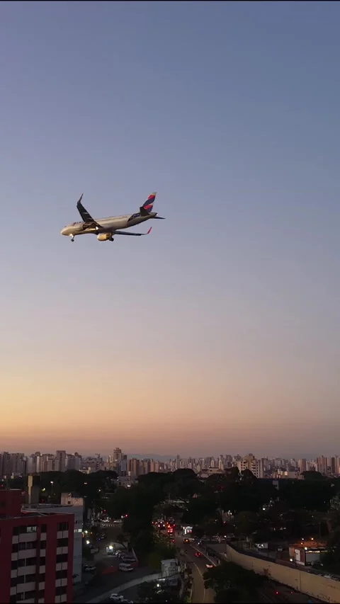 Vertical Airplane Flying Over Urban Skyline at Sunset Stock Footage 340536290