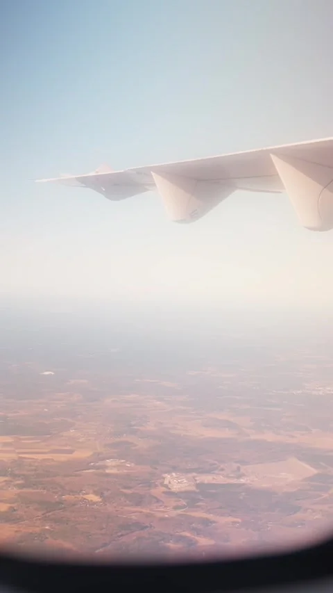 Vertical airplane window view with wing overhead and hazy farmland below Vídeos de archivo 333651474