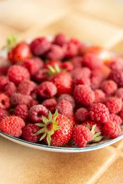Vertical and centered view of a plate of fresh strawberries and raspberries Stock Photos