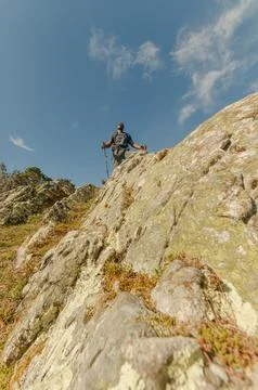 Vertical angle from below looking up at black hiker with his walking sticks Stock Photos