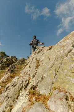 Vertical angle from below looking up at smiling black hiker with his walking Stock Photos