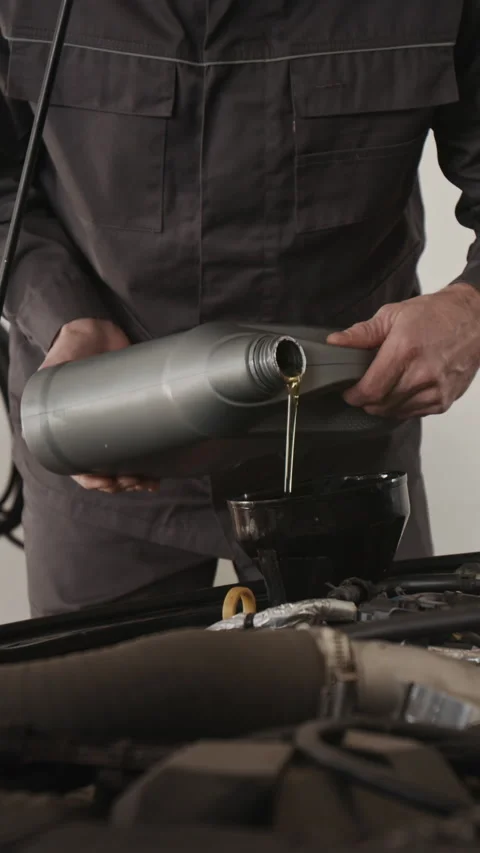 Vertical of Anonymous Car Mechanic Changing Engine Motor Oil in Garage Stock Footage 329461906
