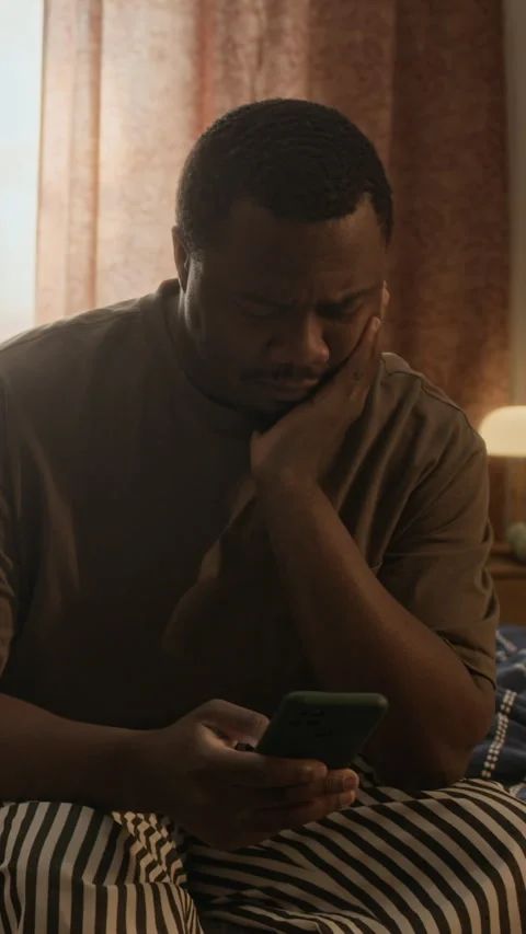 Vertical of Anxious Black Man Sitting and Looking at Smartphone at Night Vídeo Stock 337713852