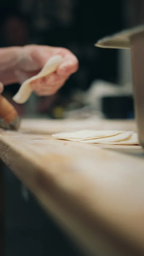 Vertical artistic low-angle view of stacked dumpling wrappers on wooden board Stock Footage 333897647