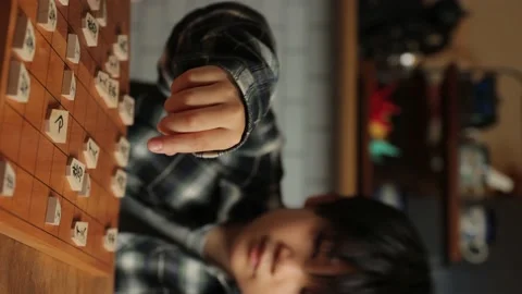 Vertical : Asian boy playing Shogi, Japanese chess at home. 30P Stock Footage 221411766