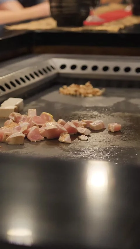Vertical of Asian chef slising chicken meat for the audience on a large stove Stock Footage 278476161
