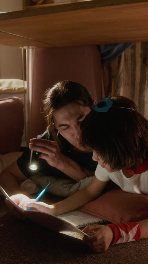 Vertical of Asian Father and Multiethnic Boy Drawing in Notebook with Flashlight Stock Footage 336175969