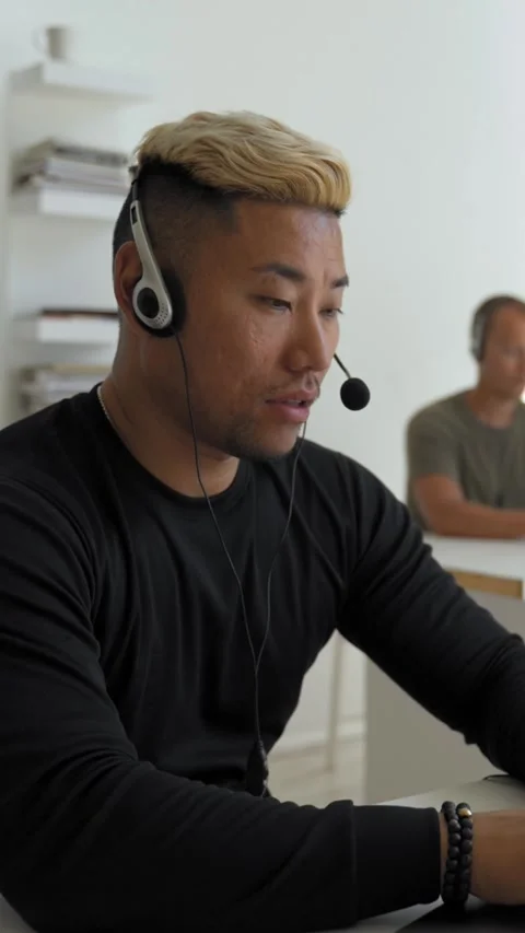 Vertical of Asian guy consultant with headset listens to customer Stock Footage 276620561