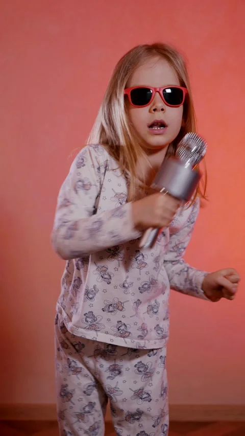 Vertical. Aspiring pop star in patterned pajamas belts out a tune and dances fun Stock Footage 307289492