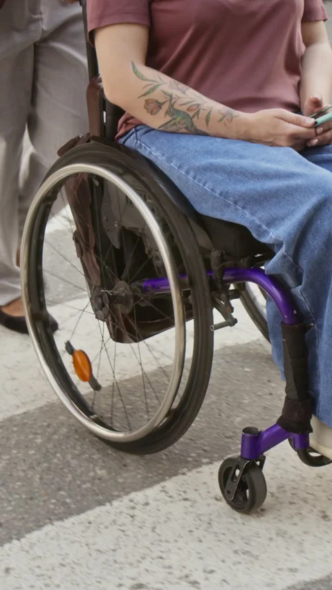 Vertical of Assistant Pushing Woman with Disability in Wheelchair on Crosswalk Vidéo 343783603