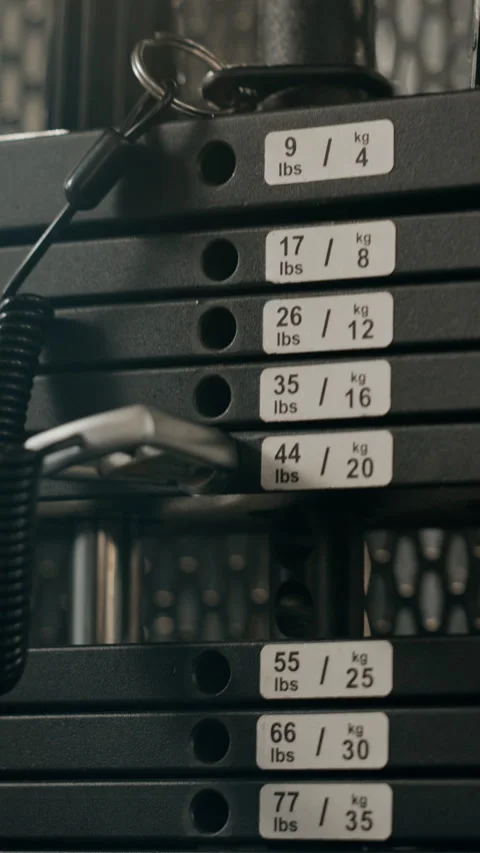 Vertical of Athlete Adjusting Weight Stack Pin on Gym Machine for Training Stock Footage 345199233