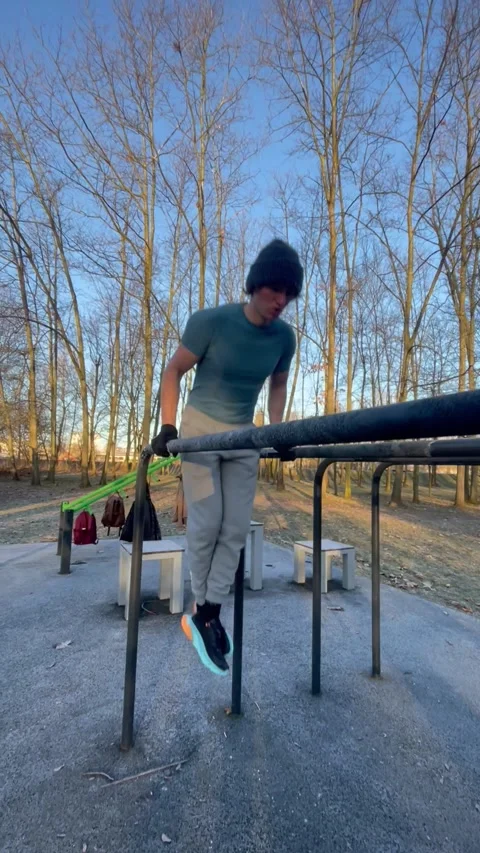 Vertical athlete doing dips on outdoor bars in cold winter park workout Stock Footage 325647640