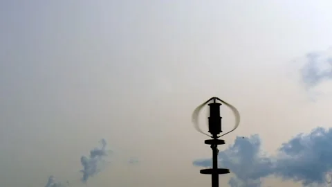 Vertical axis wind turbine producing electric energy while spinning against sky. Stock Footage 148650604