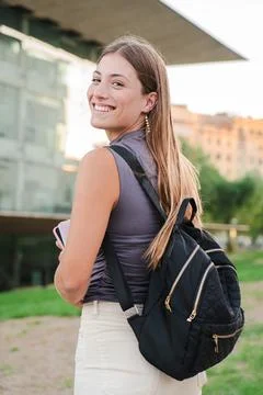 Vertical back view of a happy young student female looking at camera enjoying Stock Photos