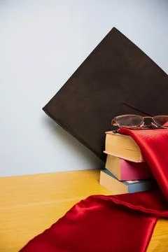 Vertical background of academic hat graduation stole on a stack of books Stock Photos