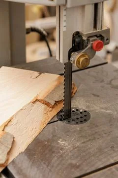 Vertical bandsaw cutting rough timber board on workbench in carpentry worksho Stock Photos