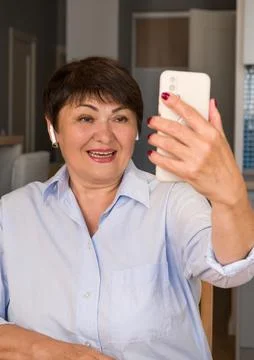 VErtical banner of elder woman using smarphone for communicaton with her chil Stock Photos