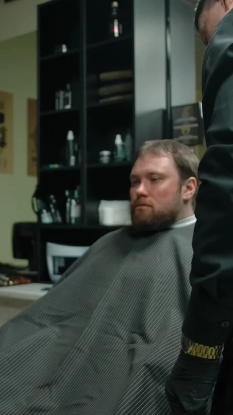 Vertical of Barber rotating the customer for a convenient haircut in the Stock Footage 276918109