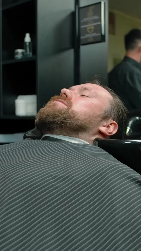 Vertical of The barbershop client rests before the master begins to cut. Stock Footage 276843769