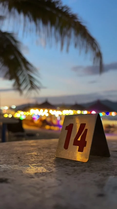 Vertical beach cafe table number fourteen close up. And glowing background at Stock Footage 343327510