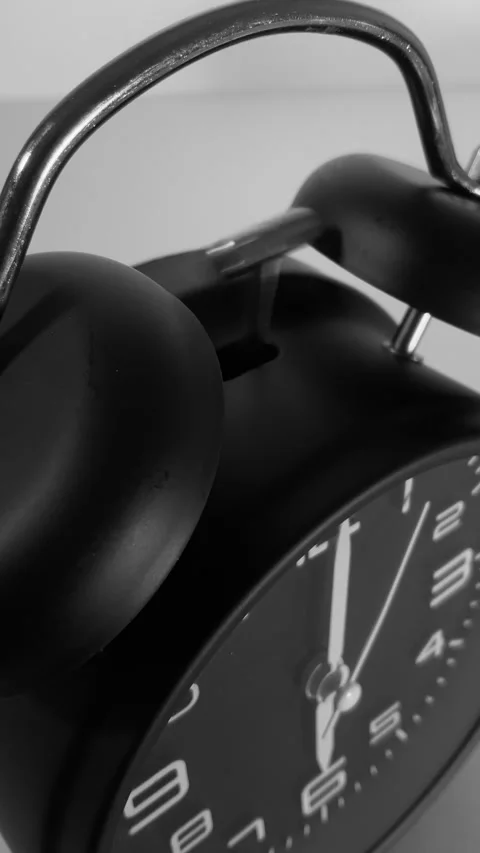 Vertical - A black alarm clock, with the hammer striking the bells at 6 o’clock. Stock-Footage 282970480