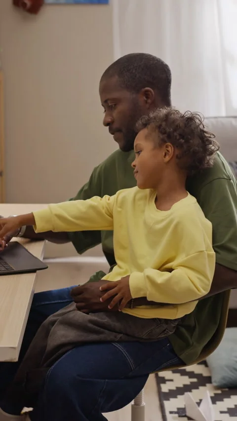 Vertical of Black Father Working on Laptop at Home with Son on His Lap Stock Footage 345493474