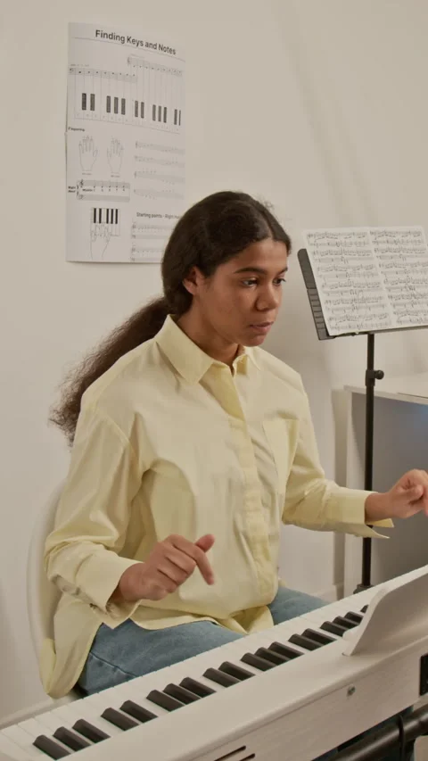 Vertical of Black Girl Practicing Digital Piano with Sheet Music in Lesson Stock Footage 339189241