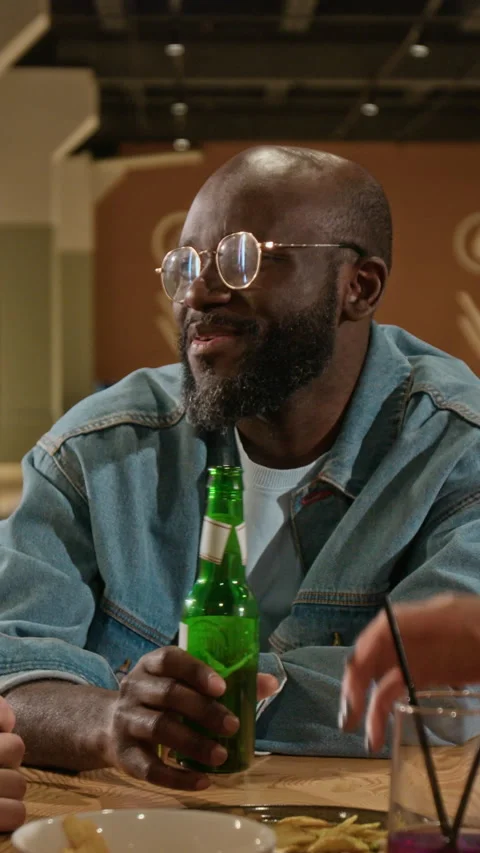Vertical of Black Man Laughing and Toasting Beer with Friends at Bowling Alley Stock Footage 337098711