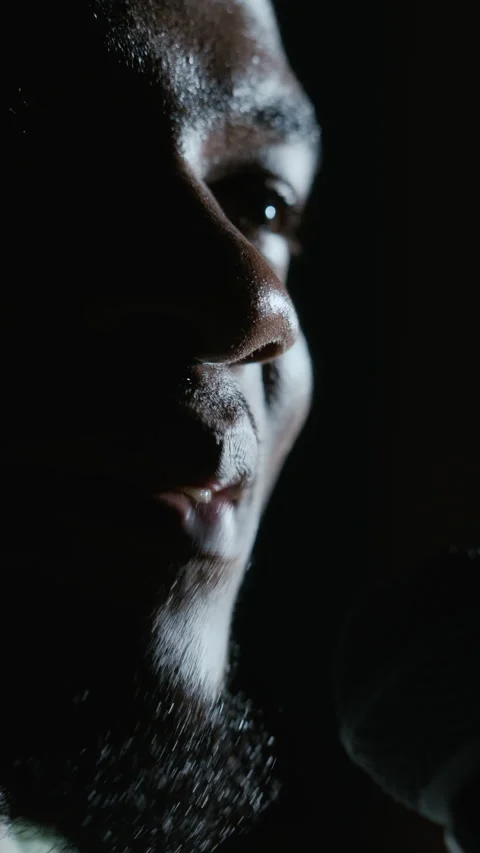 Vertical of Black Man Speaking into Microphone on Dark Stage in Theater Stock Footage 344534917