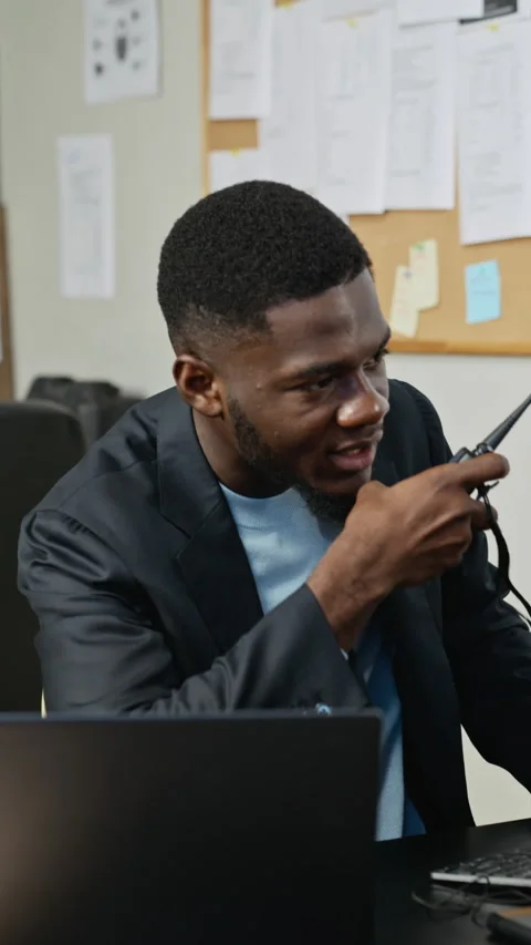 Vertical of Black Man Using Walkie Talkie with Laptop in Cybersecurity Office Stock Footage 346813501