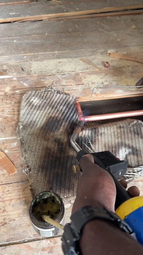 Vertical. Black plumber soldering copper pipe under wooden floor. Vídeos de archivo 297260895