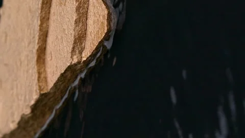 Vertical black water surface motion, splashes, waves, ripples with golden stone Video stock 256125367