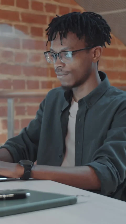 Vertical of Black Young Web Developer Working on Laptop at White Office Desk Video stock 322632421