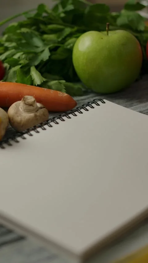 Vertical of Blank notepad for recipe amidst vegan food on table Stock Footage 276763926
