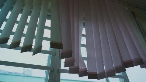 Vertical blinds partially open on window with view of buildings outside. Light Video stock 276320540