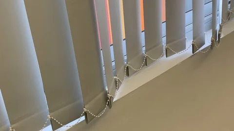 Vertical blinds undulate from soft air movement shot with diagonal orientation Stock Footage 114497503