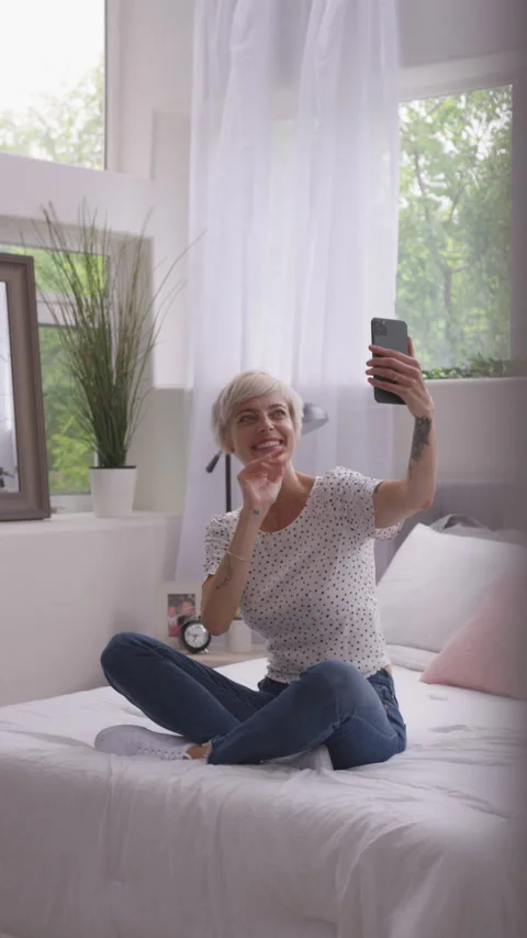 Vertical of Blonde with Pixie Haircut Smiling and Waving as She Skypes Stock Footage 208777689