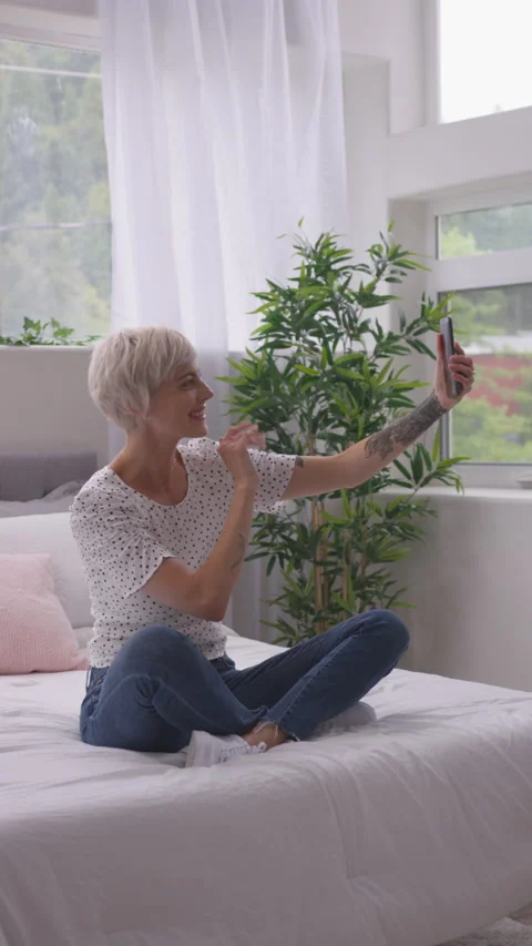 Vertical of Blonde with Pixie Haircut Waving as She Skypes From Bedroom Stock Footage 208777772