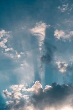 Vertical blue sky with clouds and sun shining through Stock Photos