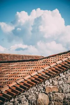 Vertical blue sky with clouds and a stone house with roof. Foto stock