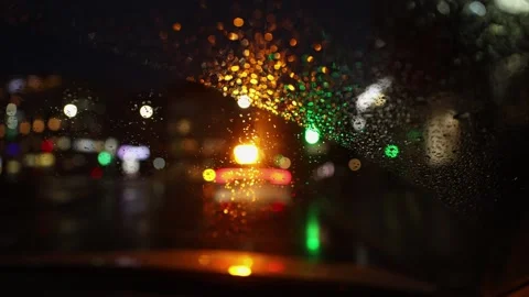 Vertical. Blurred background of night city traffic through wet car windshield. Video stock 270163335