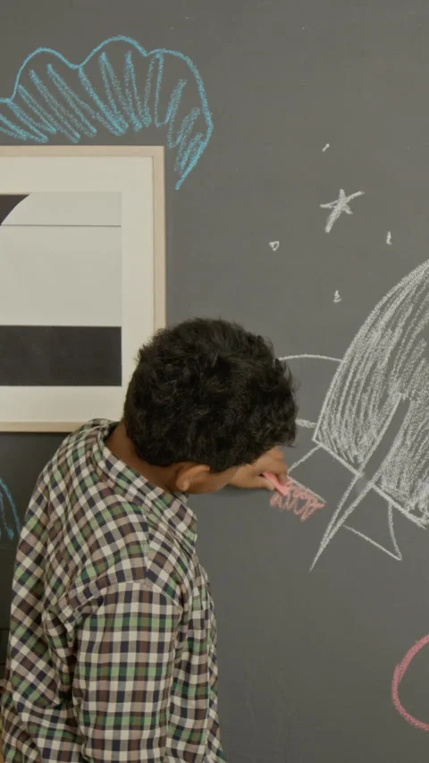 Vertical of Boy Drawing Space Rocket on Blackboard with Chalk Stock Footage 342487898