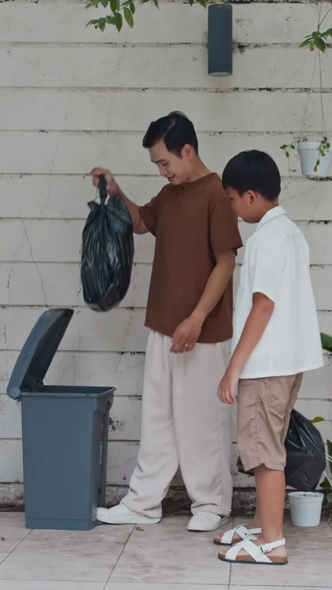 Vertical of Boy Helping Father Throwing Litter Away Stock Footage 289173595