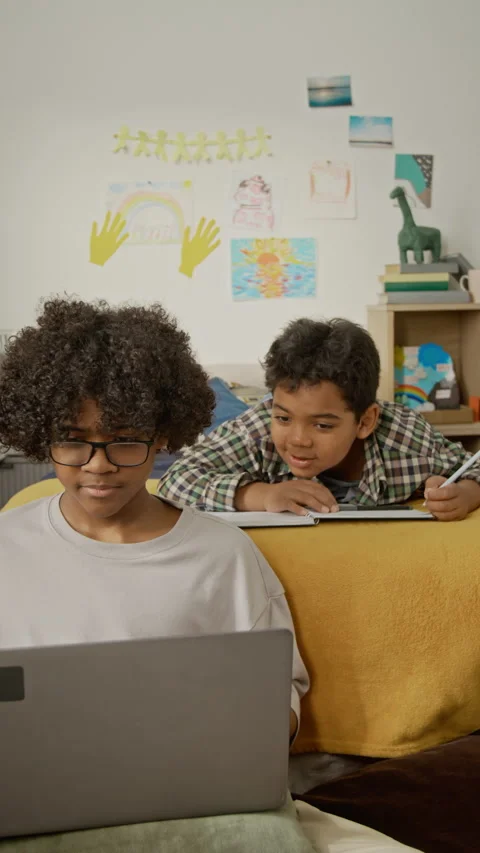 Vertical of Boys Doing Homework Using Laptop, Writing in Notebook Vídeo Stock 342508161