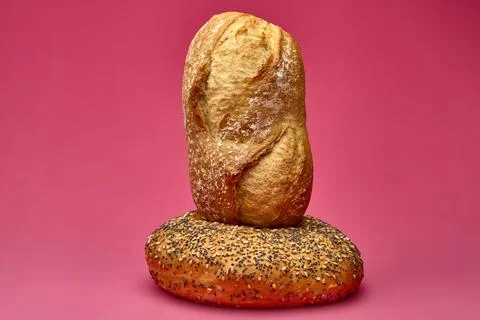 Vertical bread roll on another roll over pink background Stock Photos