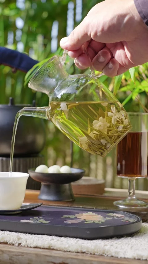Vertical: Brewed green tea is poured into a small white teacup. Stock Footage 347245669
