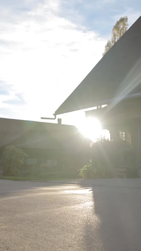 Vertical of Bright sun rises from behind cottage house with grey roof Stock Footage 274153080