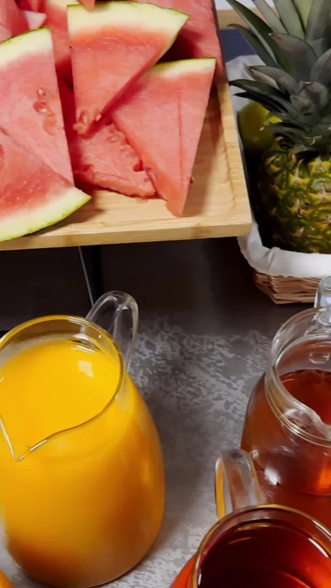 Vertical buffet close-up with watermelon slices, orange juice, pineapple Stock Footage 336937942
