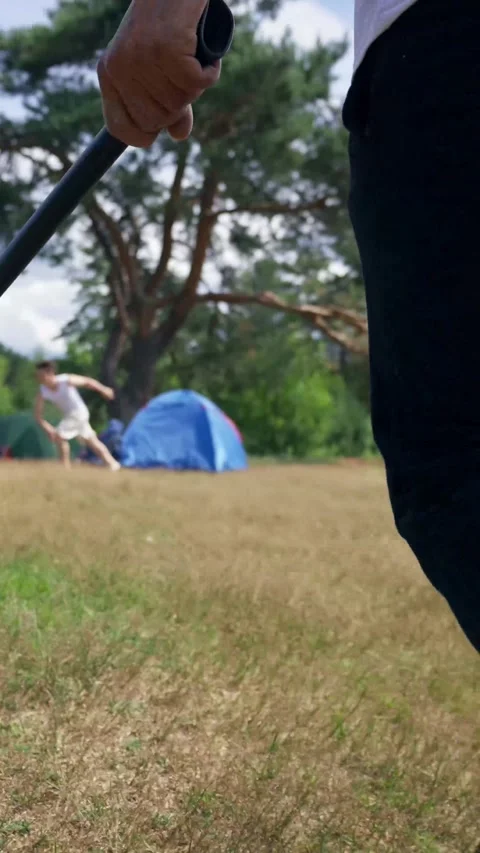 Vertical of Bully runs with axe to young couple at tent on forest meadow Stock Footage 276385185
