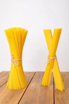 A vertical bunch and a bunch of raw spaghetti tied with string. Bundle on a w Stock Photos